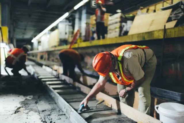 Amtrak construction worker levels concrete at track 10.